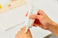 Hand dabbing Kinship Self Reflect SPF 32 Probiotic Moisturizing Sunscreen onto other hand