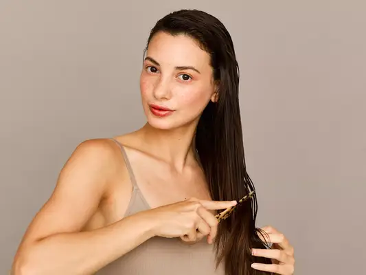 woman combing through ends of hair 