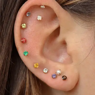 An ear with a gradient of rainbow colored studs.