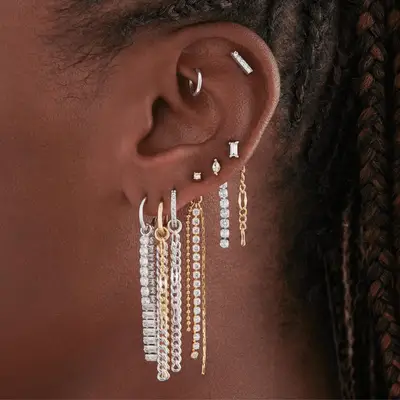 An ear with dangly, bejeweled chain earrings.