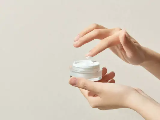 Image of a hand holding a jar of cream