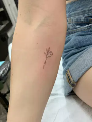 close up of micro flower tattoo on forearm in black ink