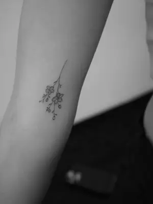 close up of cute flower tattoo upside down on forearm