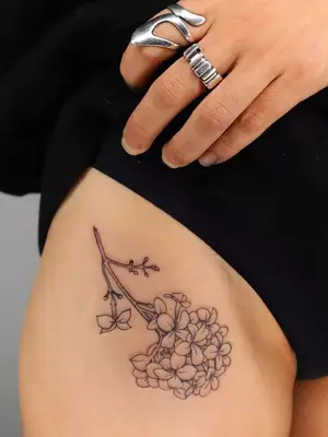 close up of flower bouquet black ink tattoo on upper thigh and bikini line area