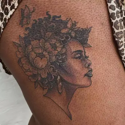 Tattoo of Black Mother Nature with flowers and butterflies in hair on torso