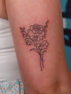 close up of floral bouquet tattoo in black ink on upper arm