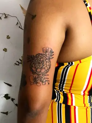 close up of botanical flower tattoo in black ink on upper arm