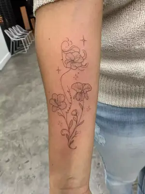 close up of swirly orchid flower design, black ink tattoo on length of arm