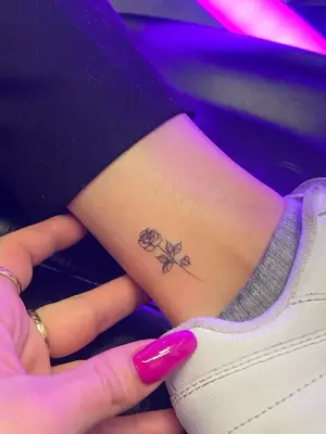 close up of black ink rose tattoo on ankle