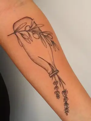 close up of vase with flowers coming out of it with fruit brand in front, black ink tattoo on forearm