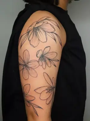 close up of open space flowers covering entirety of upper arm, black ink tattoo