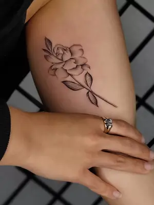 close up of garden flower tattoo in black ink on side of calf