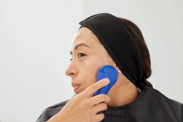 A person using the NågraCoola Sonic Facial Cleansing Brush on their cheek