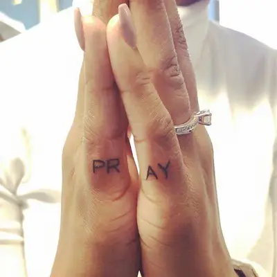 Pray set of word tattoos split between outer pinky fingers