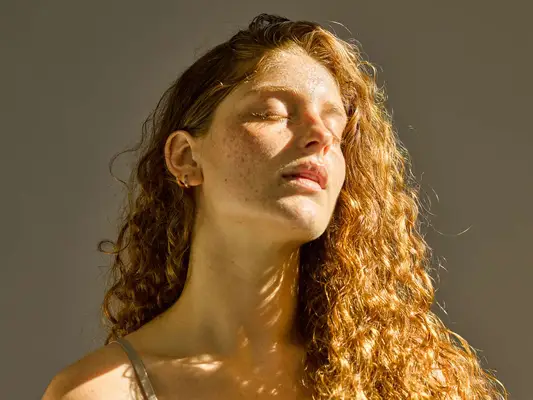 woman with long red hair sitting in sunlight