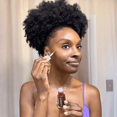 Essence Gant applying Clinique Pop Lip + Cheek Oil in Black Honey to her cheek