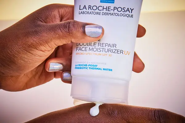 Hand squeezing La Roche-Posay Toleriane Double Repair Face Moisturizer UV With SPF 30 into the back of the other hand
