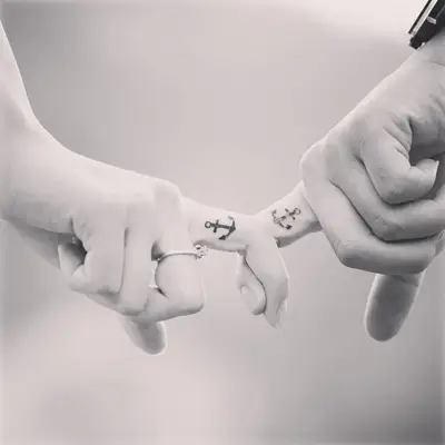 Two people with matching anchor tattoos on the ring finger