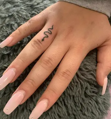 Person with a snake ring finger tattoo