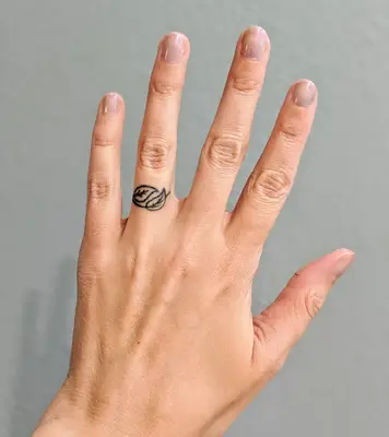 Person with leafy ring finger tattoo