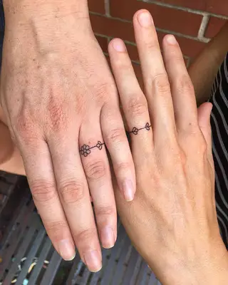 Two people with flower ring finger tattoos