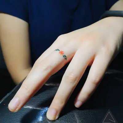 Person with a colorful flower ring finger tattoo