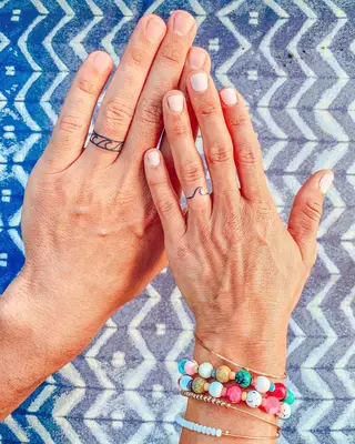 Person with a minimalist wave ring finger tattoo