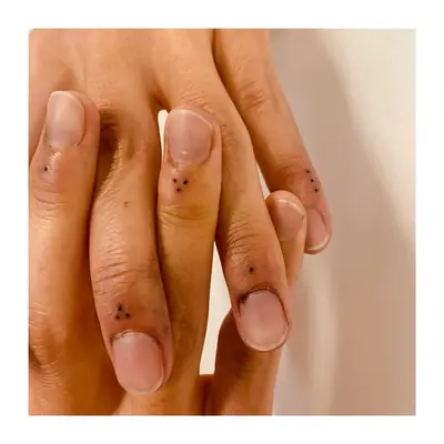 Person with delicate dot tattoos on fingers