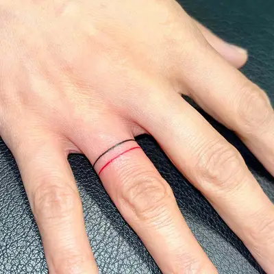 Person with layered ring tattoos on ring finger