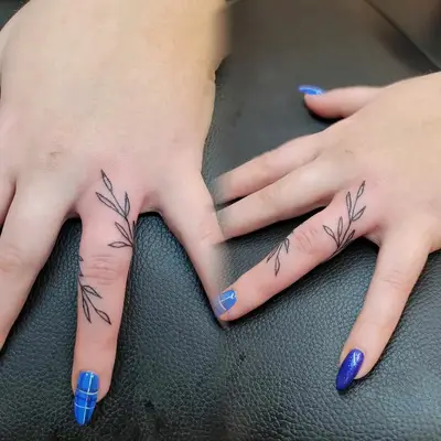 Person with a colorful dainty flower ring finger tattoo