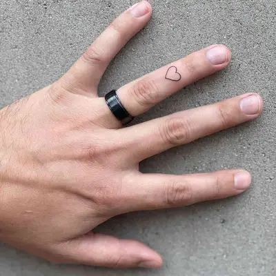 Person with heart tattoo on the ring finger