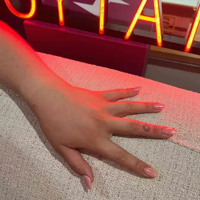 Person with sun ring finger tattoo