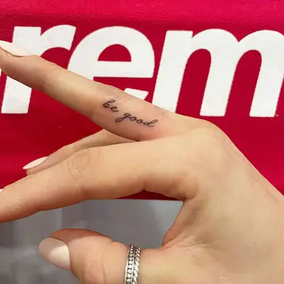 Person with a cursive ring finger tattoo