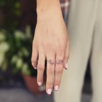 Person with angel wings finger tattoos