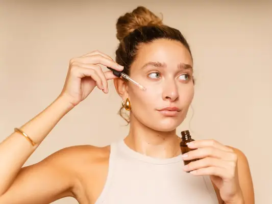 Woman applying a serum with a dropper on her face