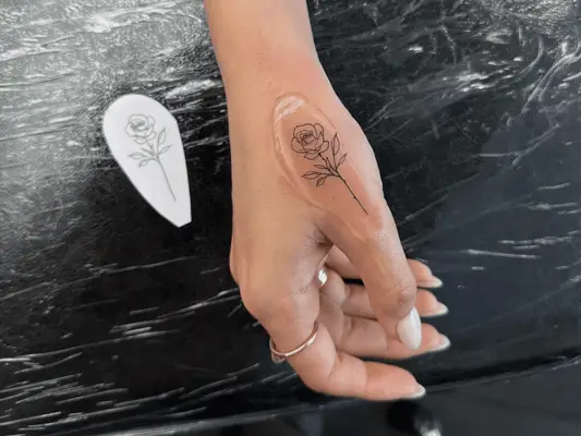 Close up of a hand with a new tattoo of a rose with ointment on it