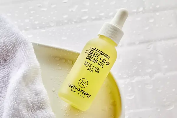 Youth to the People Superberry Hydrate + Glow Dream Oil on a white tray next to a towel 