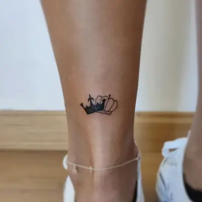 Interlocking crown tattoo on the back of the ankle