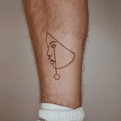 Line tattoo of a face on the outer calf