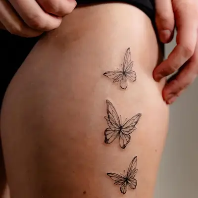 Delicate butterfly tattoos on the upper thigh
