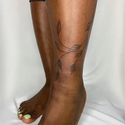Vine tattoo with leaves wrapped around lower leg