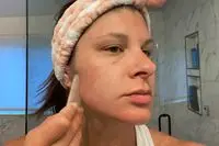 Close up of person using a Pink Moon Rose Quartz Gua Sha Facial Tool on their face