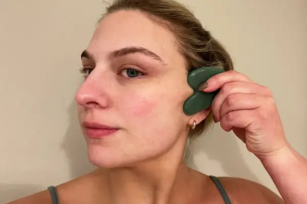 Person using a Skin Gym Jade Sculpty Heart Gua Sha Tool on their face