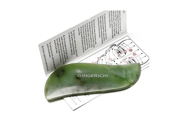 Close up of person using a Pink Moon Rose Quartz Gua Sha Facial Tool on their face