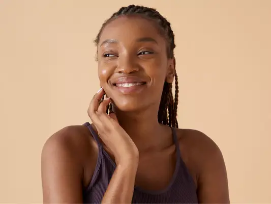 A woman with glowing skin touching her face