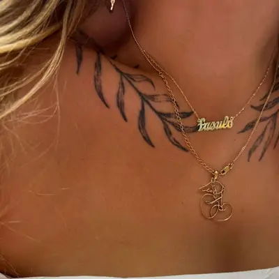 zoomed-in image of model with leafy plant tattoos in black ink on both sides of collarbone