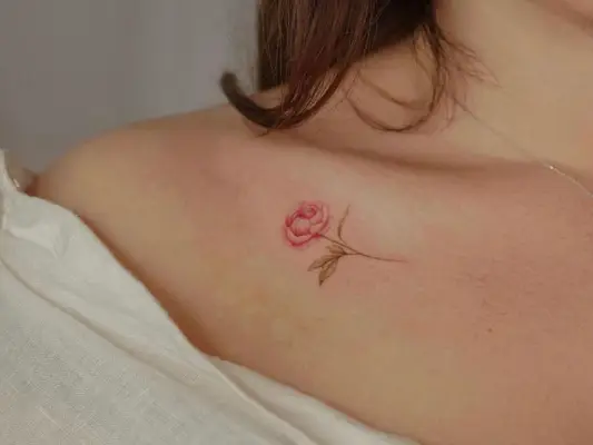 Close up of a red/pink and green peony tattoo on a collarbone 