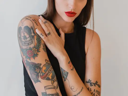 Tattooed woman with her hand on her shoulder