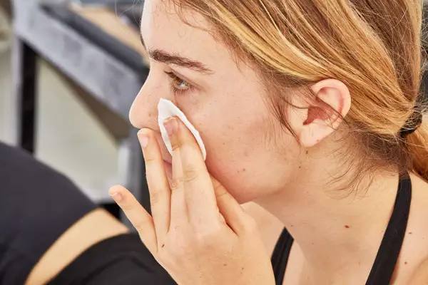 Person applying micellar water to their cheek with a cotton round