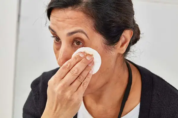 Person applying micellar water to their cheek